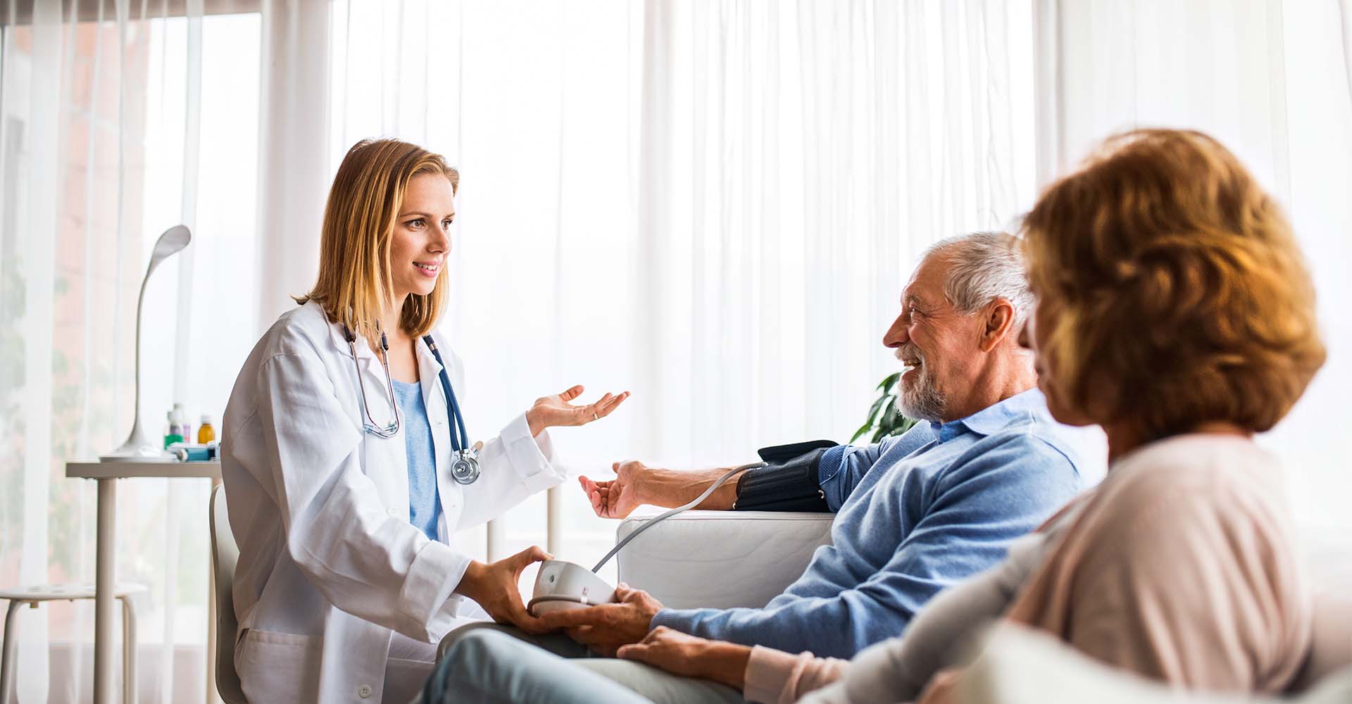 Female doctor checking blood pressure of senior man